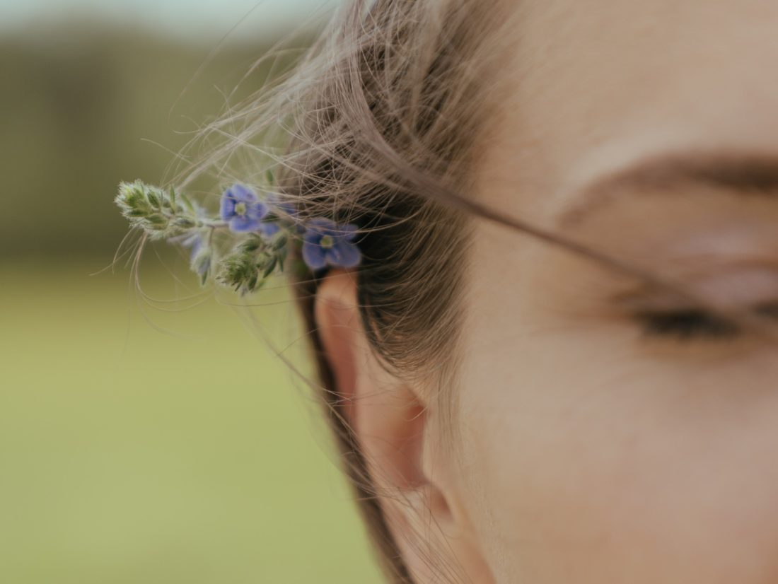 side-of-womans-face with-flower-tucked-behind-ear
