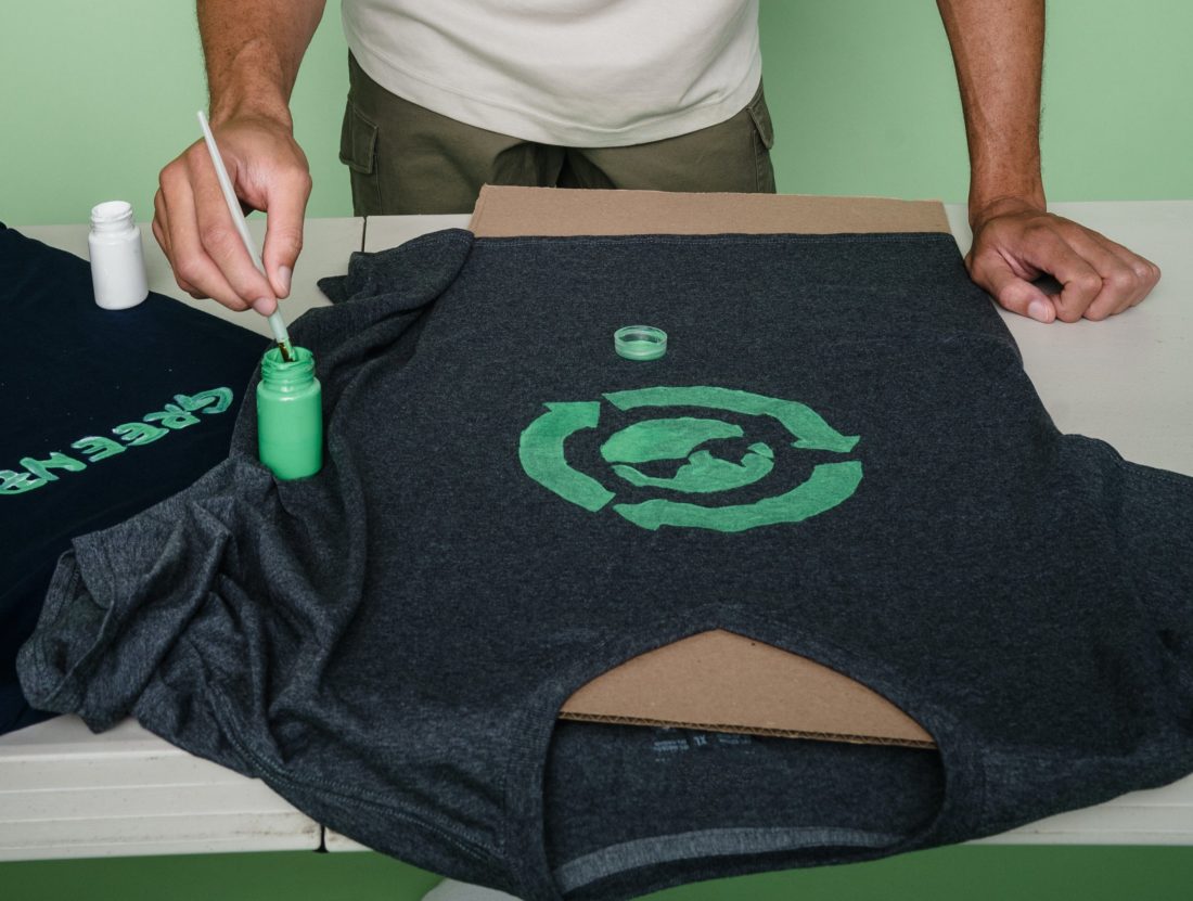man-painting-t-shirt-with-green-symbol