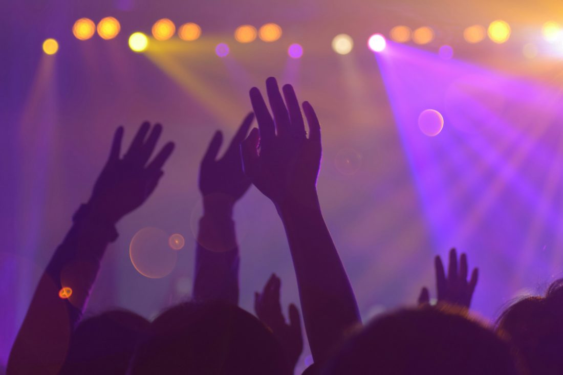 hands-raised-at-festival-with-lights-behind